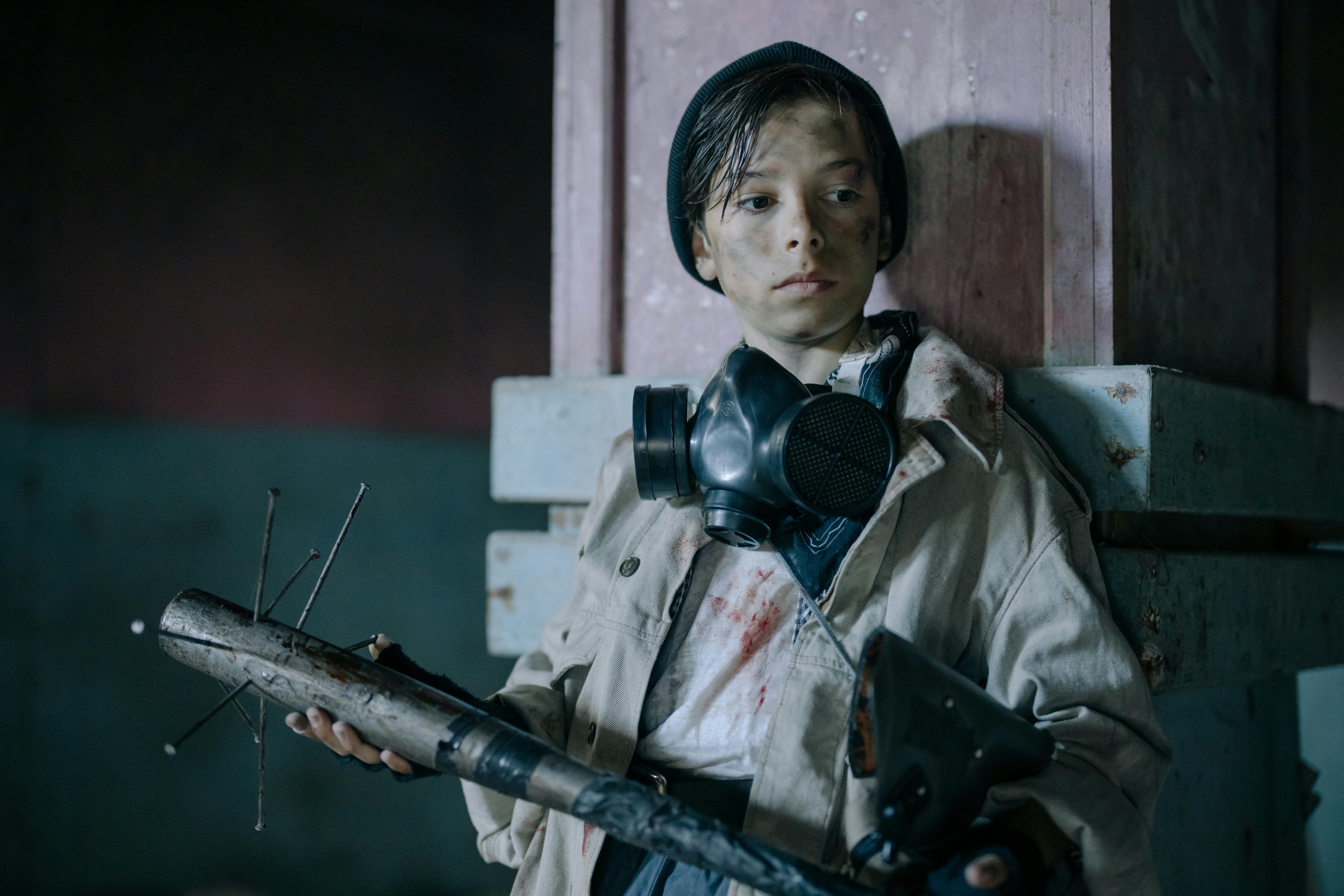 boy in gray jacket holding rifle