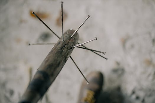 Gritty close-up image of a homemade nail bat on rough concrete background.