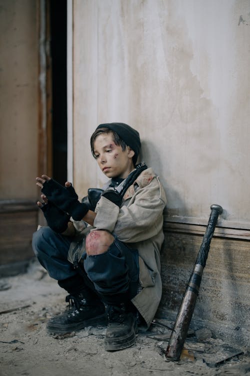 Chłopiec W Brązowo Czarnej Kurtce Siedzący Na Czarnym Metalowym Pręcie