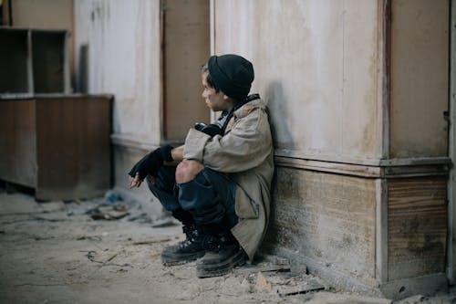 Free Man in Brown Jacket and Black Pants Sitting on Concrete Wall Stock Photo