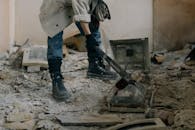 Person in Blue Denim Jeans and Black Leather Boots Standing Beside Black Metal Machine