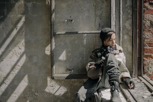 Free A young person sits in a dilapidated building, symbolizing isolation in a post-apocalypse world. Stock Photo