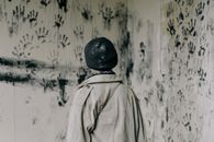 一个人站在一个布满黑色手印、令人难忘的房间里，这唤起了一种神秘和恐惧的感觉