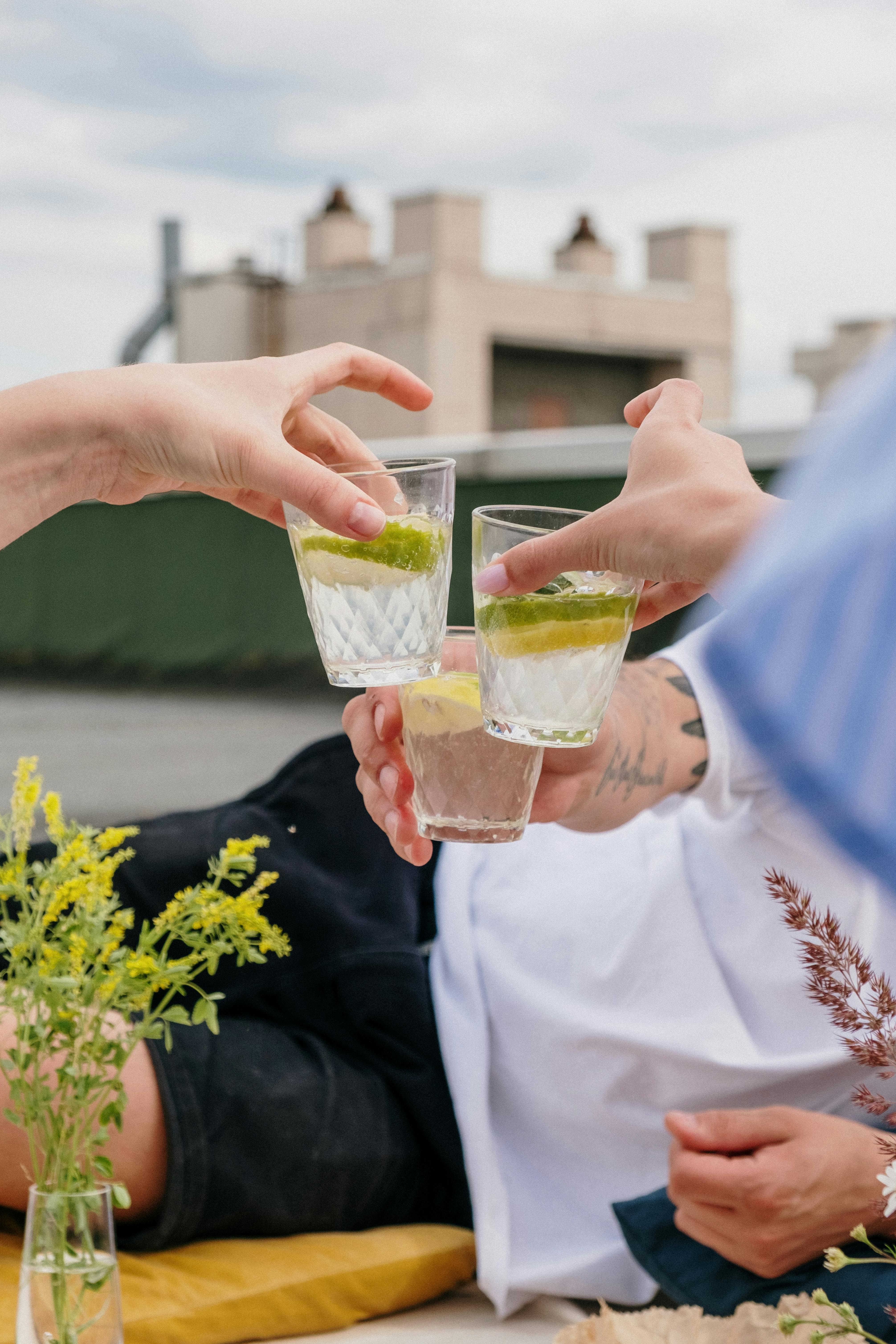 person in white long sleeve shirt holding clear drinking glass