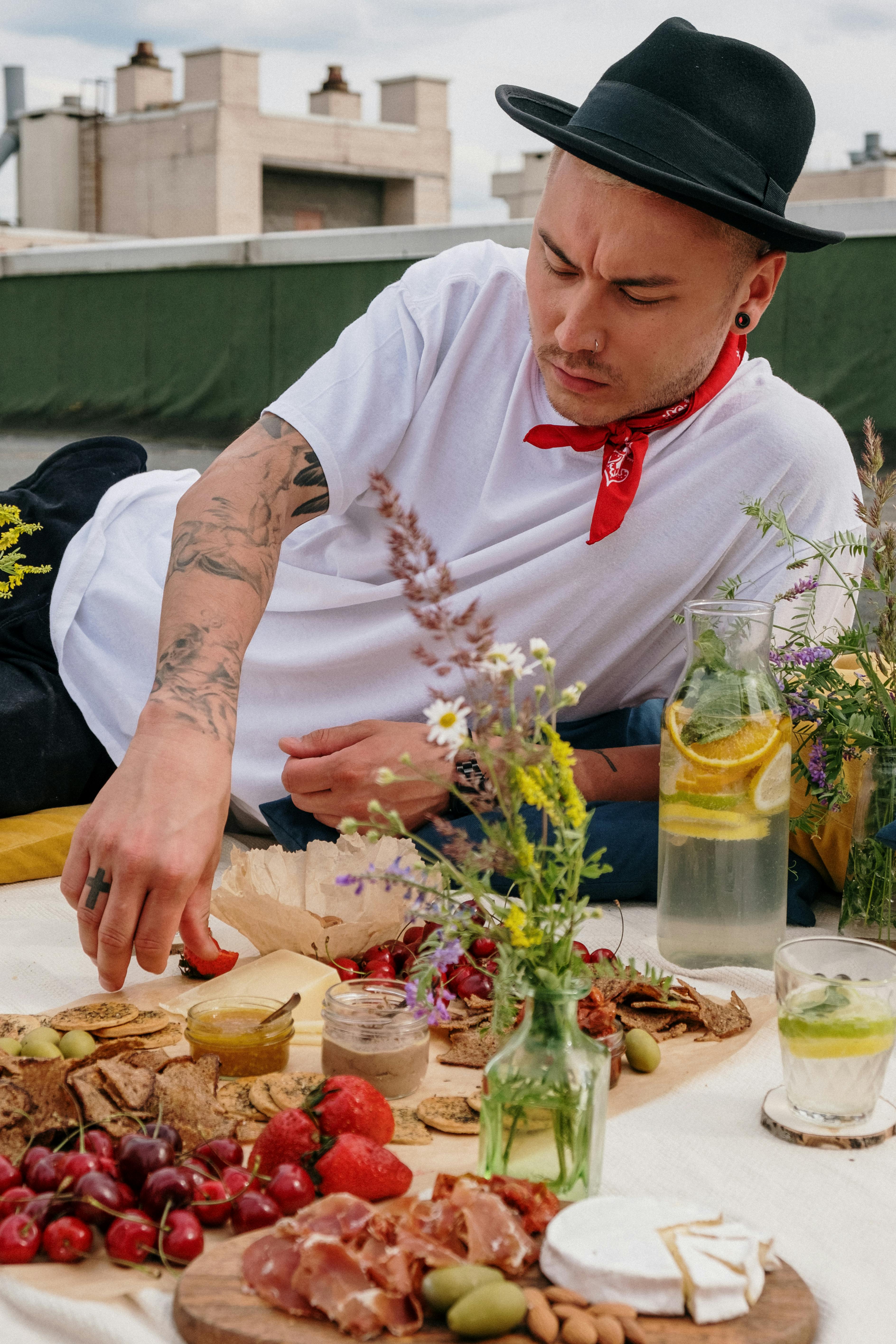 Young man enjoying a summer rooftop picnic with a variety of fresh foods and lemonade.