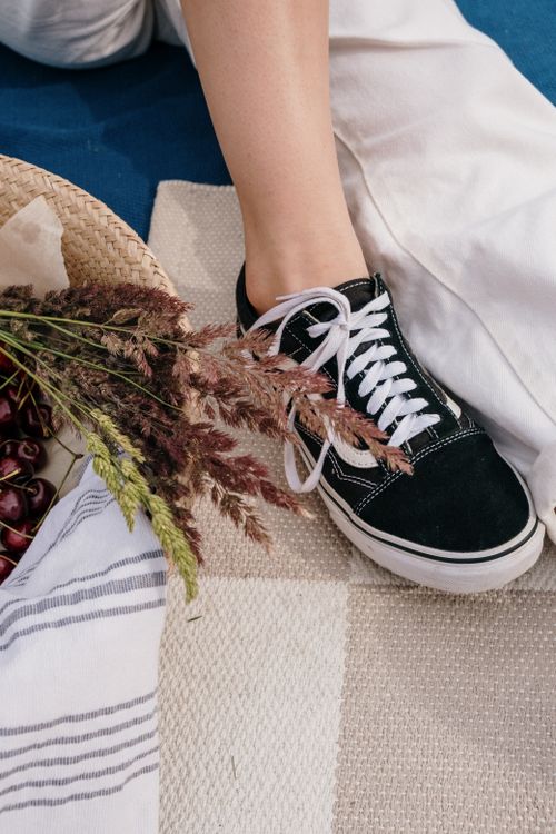 Free Casual outdoor picnic scene featuring black sneakers, a bouquet of herbs, and a woven basket. Stock Photo