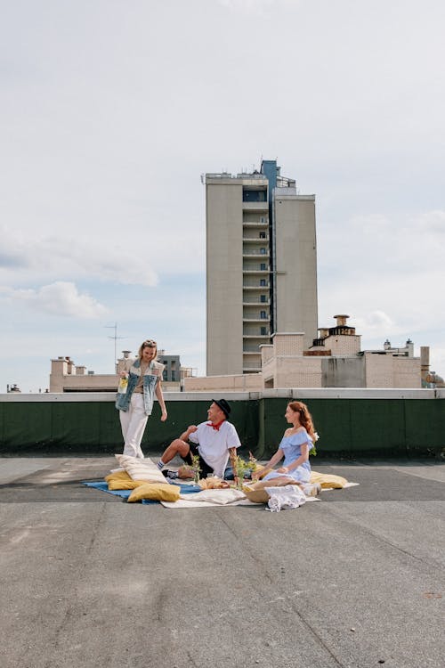 3 Women Sitting on White Textile on Gray Concrete Floor