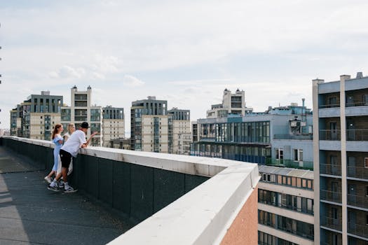 在晴朗的日子里，三个朋友在城市屋顶上放松身心，欣赏城市天际线