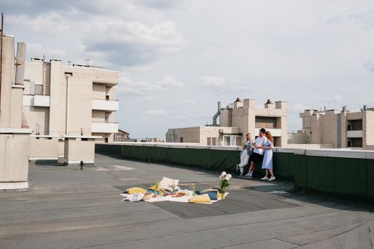 一群朋友在城市屋顶上，趁着晴朗的天空享受夏季野餐
