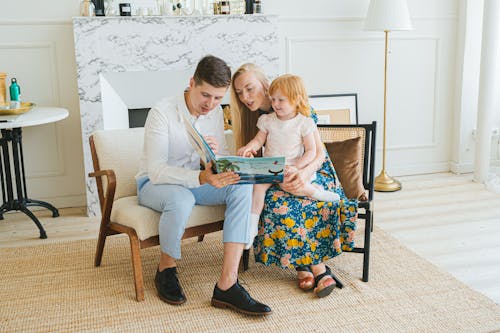 Free Photo of Parents Reading a Book with Their Daughter Stock Photo