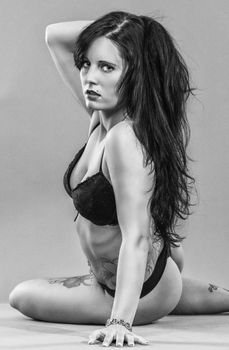 Seductive black and white portrait of a woman in lingerie posing in studio.