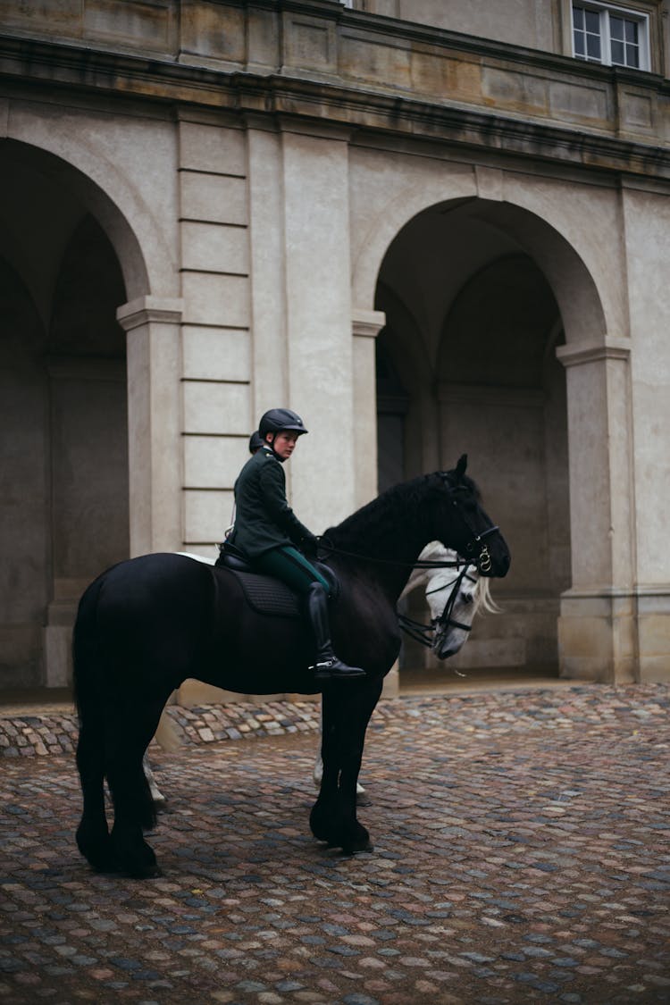 A Woman In Military Uniform Riding A Black Horse