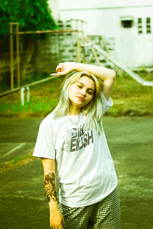 Photo of a Stylish Woman in a White Shirt Posing with Her Hand on Her Head