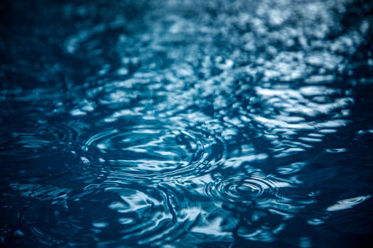 Calm water surface with ripples and raindrops, creating a serene abstract pattern.