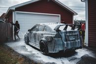 Faceless man washing luxury sports car in yard of house