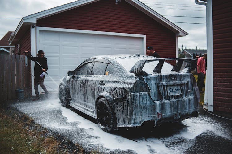 Faceless Man Washing Luxury Sports Car In Yard Of House