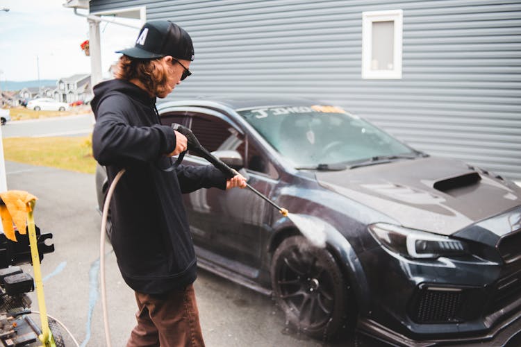 Concentrated Man Washing Automobile At Car Wash