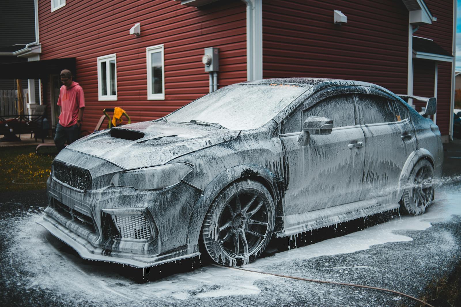 African American worker at a car wash with a foam-covered car