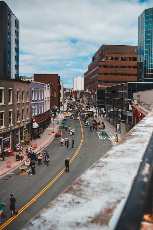 From above of people on asphalt road surrounded by tall contemporary constructions in daylight