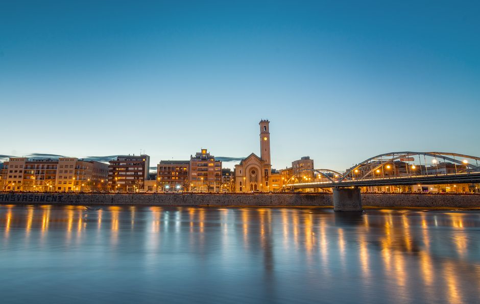 Vista escénica del horizonte de la ciudad de Tortosa con el puente y el río al atardecer, creando una escena urbana tranquila.