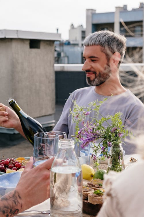 Man in White Crew Neck T-shirt Holding Wine Bottle