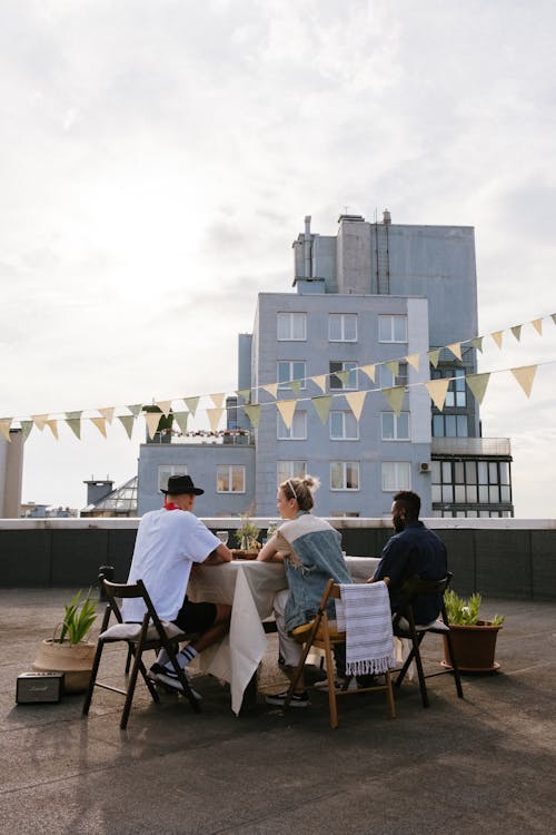 3 Men Sitting on Chair Near White Concrete Building