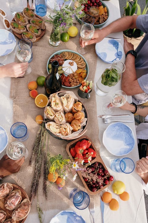 Free Person in Blue T-shirt Sitting on Chair in Front of Table With Foods Stock Photo