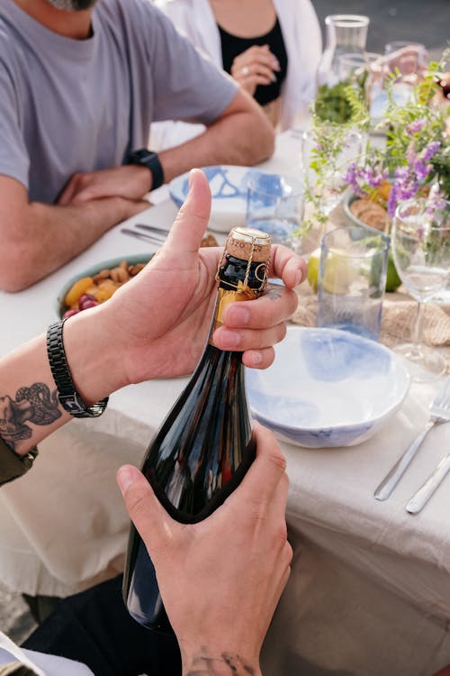 Person Holding Black Glass Bottle