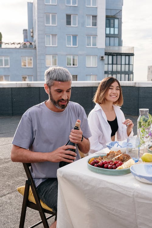 Man in Blue Crew Neck T-shirt Sitting Beside Woman in White Crew Neck T-shirt