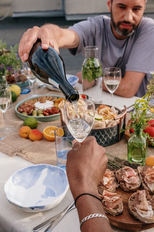 Man in Blue Polo Shirt Pouring Wine on Clear Wine Glass