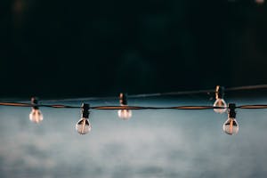 Small switched off electric lamps on long wire strained above gray blurred surface