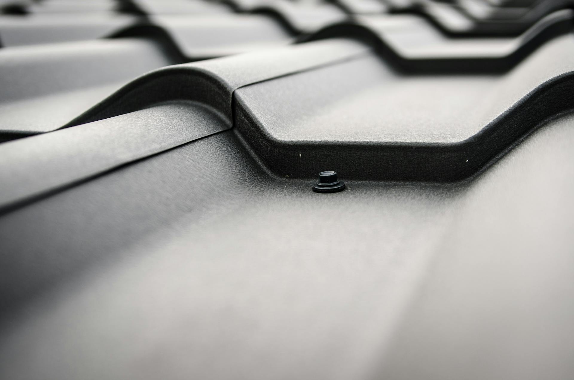 Detailed close-up of a black steel roof with prominent rivets and tiles.