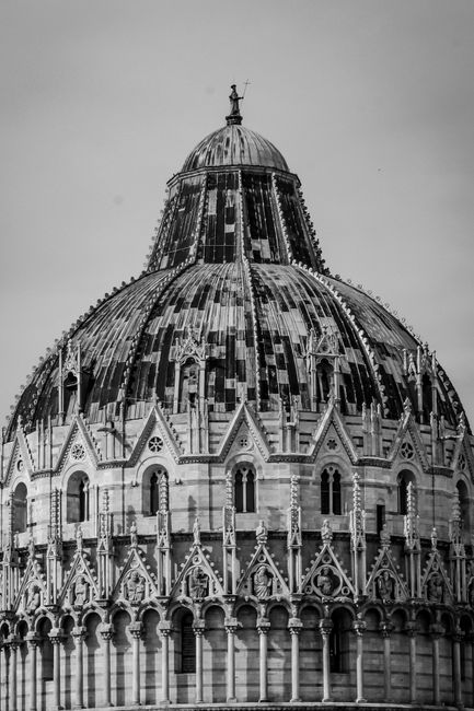 Monochrome image focusing on the intricate details of the Pisa Baptistery's dome in Italy.