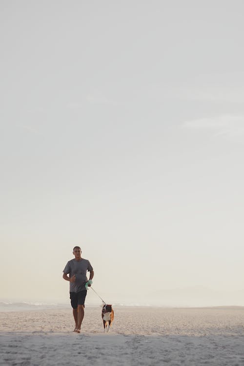 Man Walking Dog on Leash on Seashore