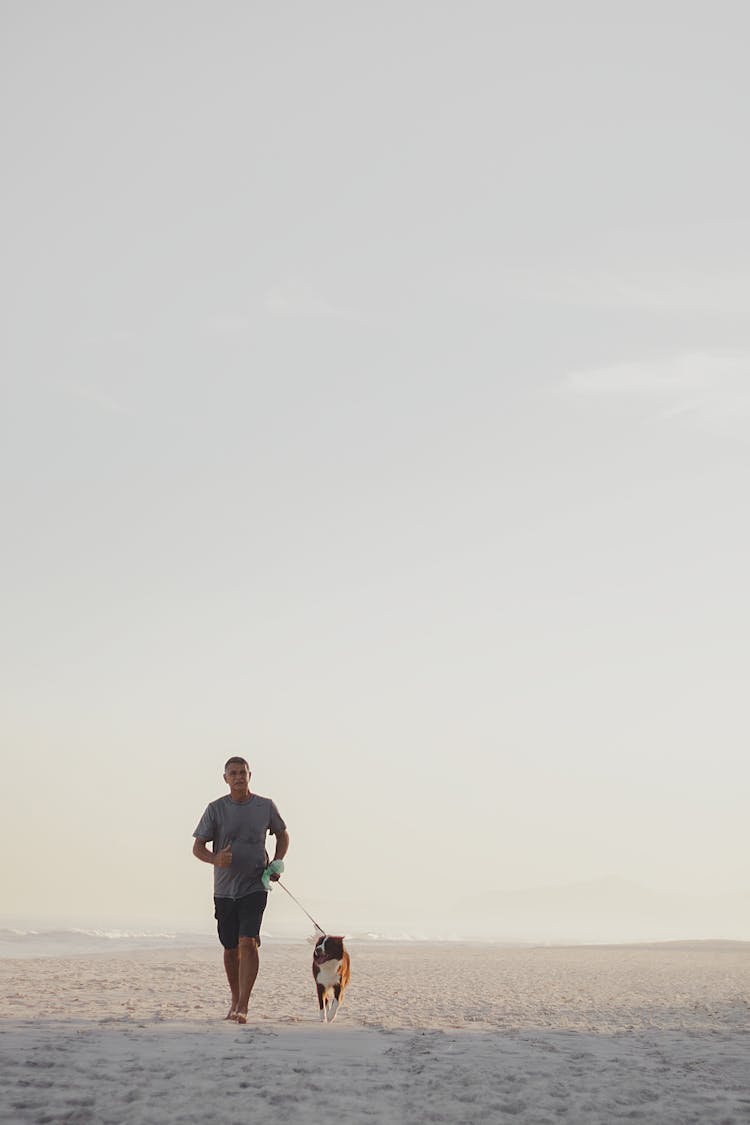 Man Walking Dog On Leash On Seashore