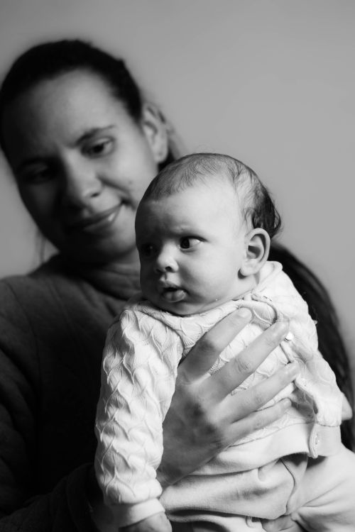 Free Black and white crop smiling mother with cute little newborn baby on laps Stock Photo