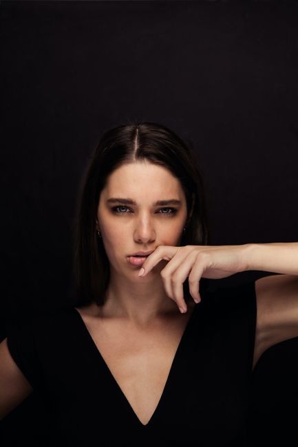 Elegant portrait of a woman with a dramatic pose against a dark background.