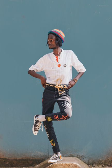 Fashionable adult with vibrant attire striking a pose against a teal wall in Nairobi, Kenya.