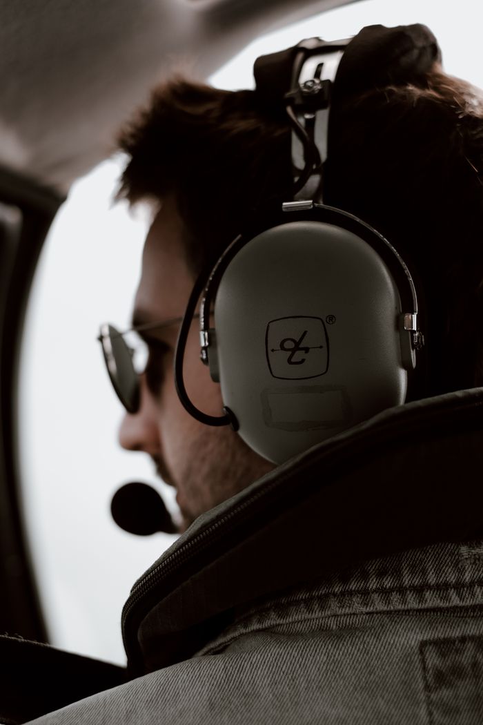 Pilot in cockpit wearing headset and sunglasses