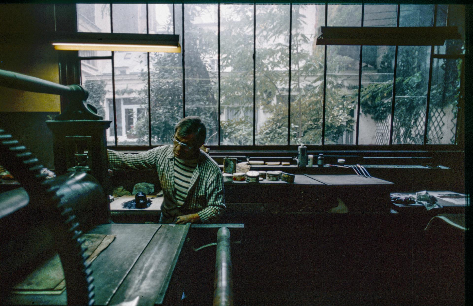 A craftsman operating a vintage printing press in a Parisian workshop, surrounded by tools and materials.
