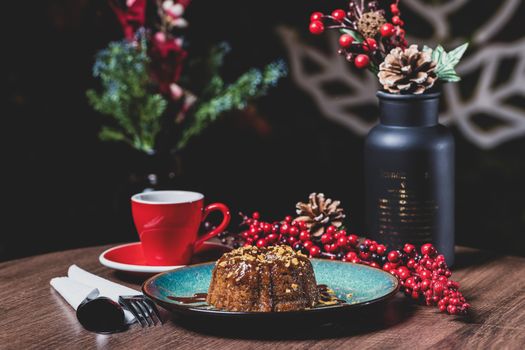 Chocolate cake on a plate with holiday decor and a red mug, creating a cozy winter feel.