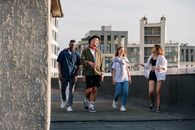 四个年轻人走在屋顶上，一起享受城市风景和夏日阳光