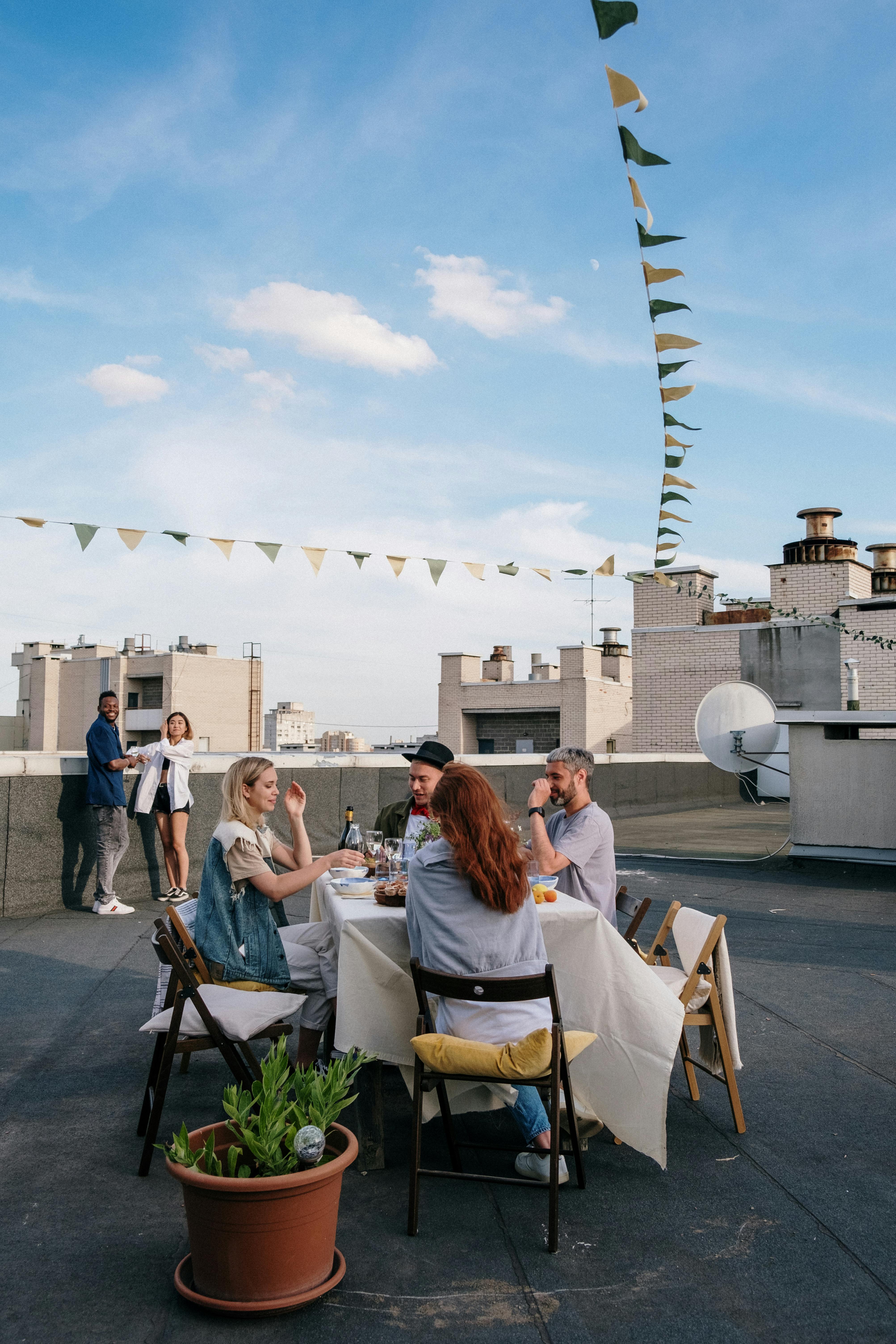 一群朋友在屋顶上享用美食，那里有城市景观和夏日氛围