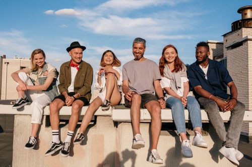 Free Diverse group of friends laughing and relaxing on a sunny rooftop. Stock Photo