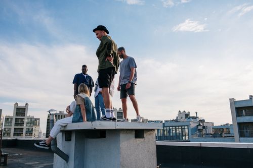 Free Friends enjoying a summer day on a rooftop with urban skyline backdrop. Stock Photo