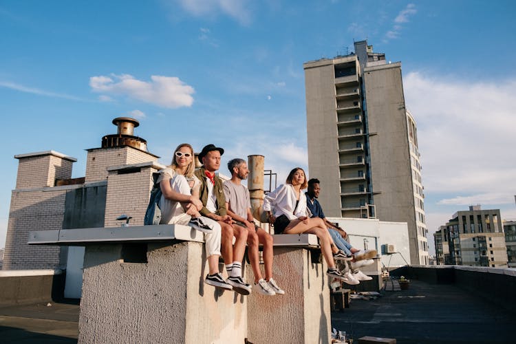 Group Of People Sitting On Gray Concrete Wall