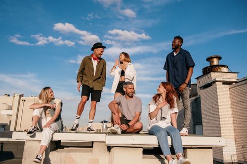 Free Friends enjoying a sunny day on a rooftop, showcasing urban lifestyle and freedom. Stock Photo