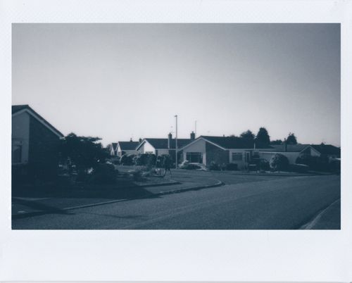 Free Grayscale image of a quiet suburban neighborhood street with houses and trees. Stock Photo