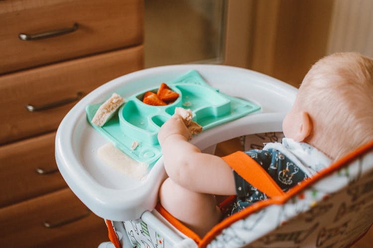 Baby In A High Chair Eating Food