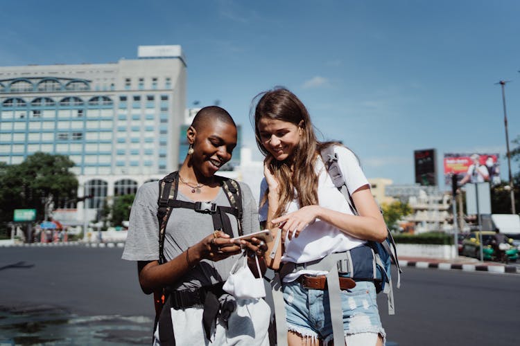 Photo Of Friends Looking At A Smartphone While Smiling